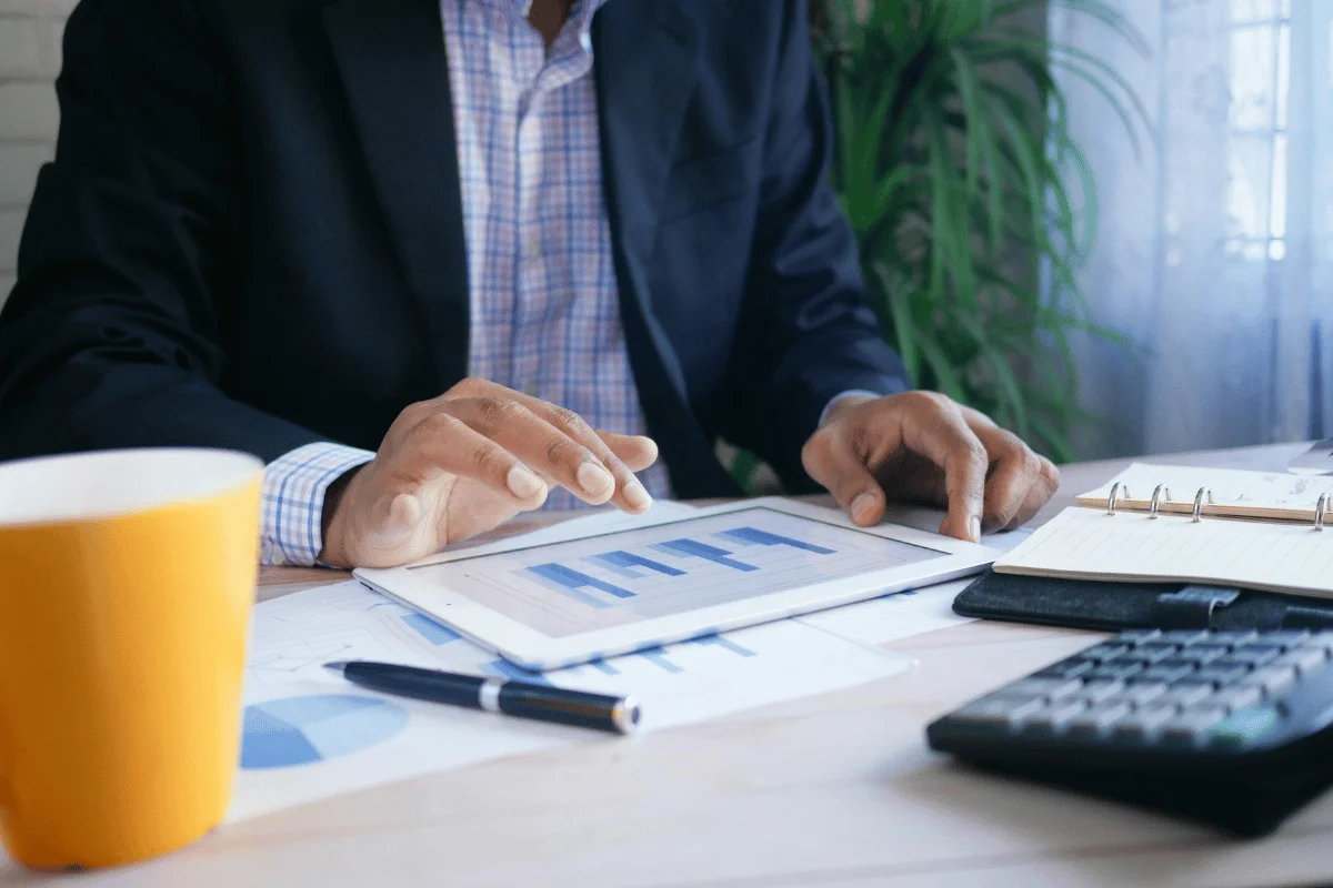 Businessman in a suit analyzing data on a tablet at his desk.