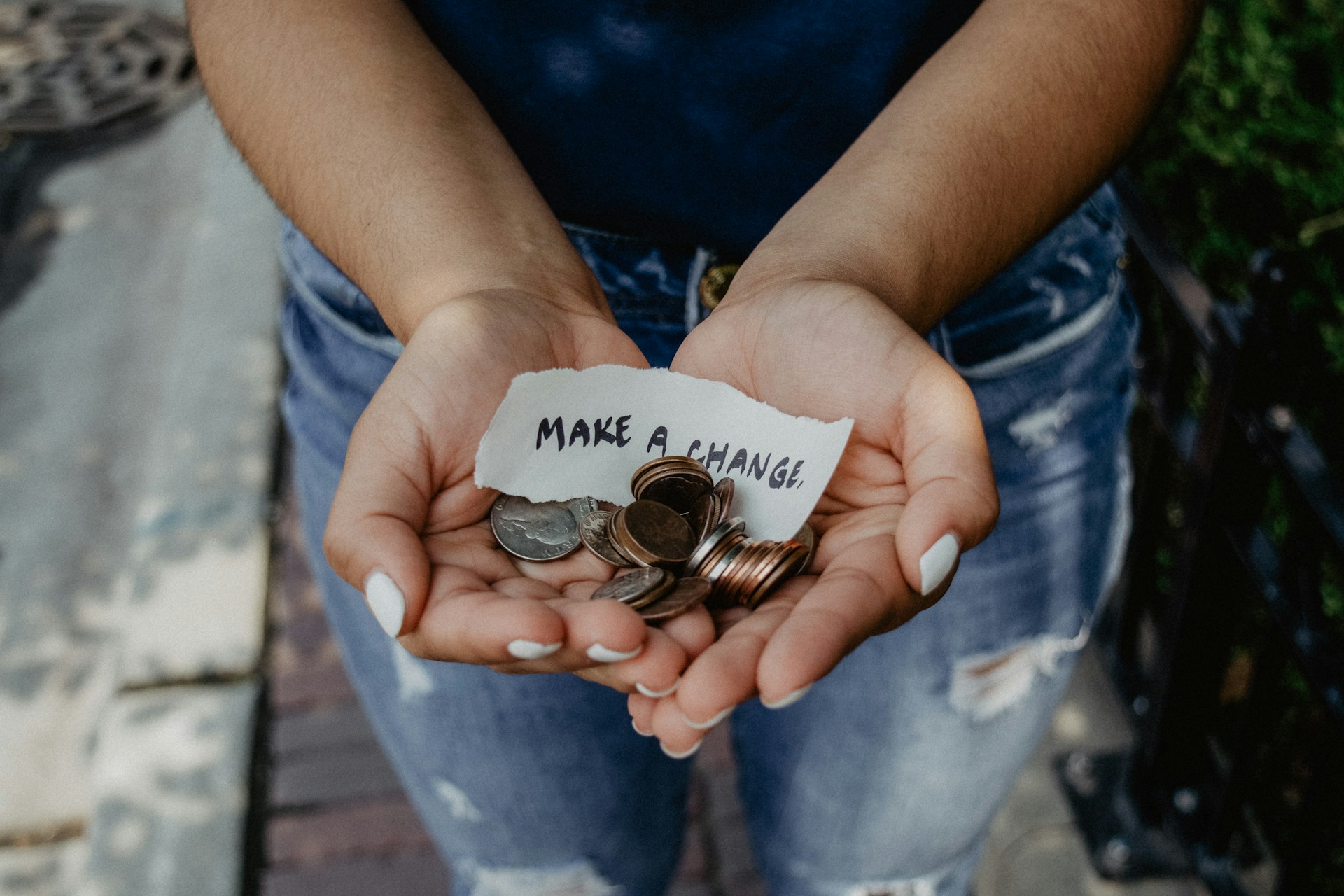 A woman holding out coins and a sign that says, "Make a change."