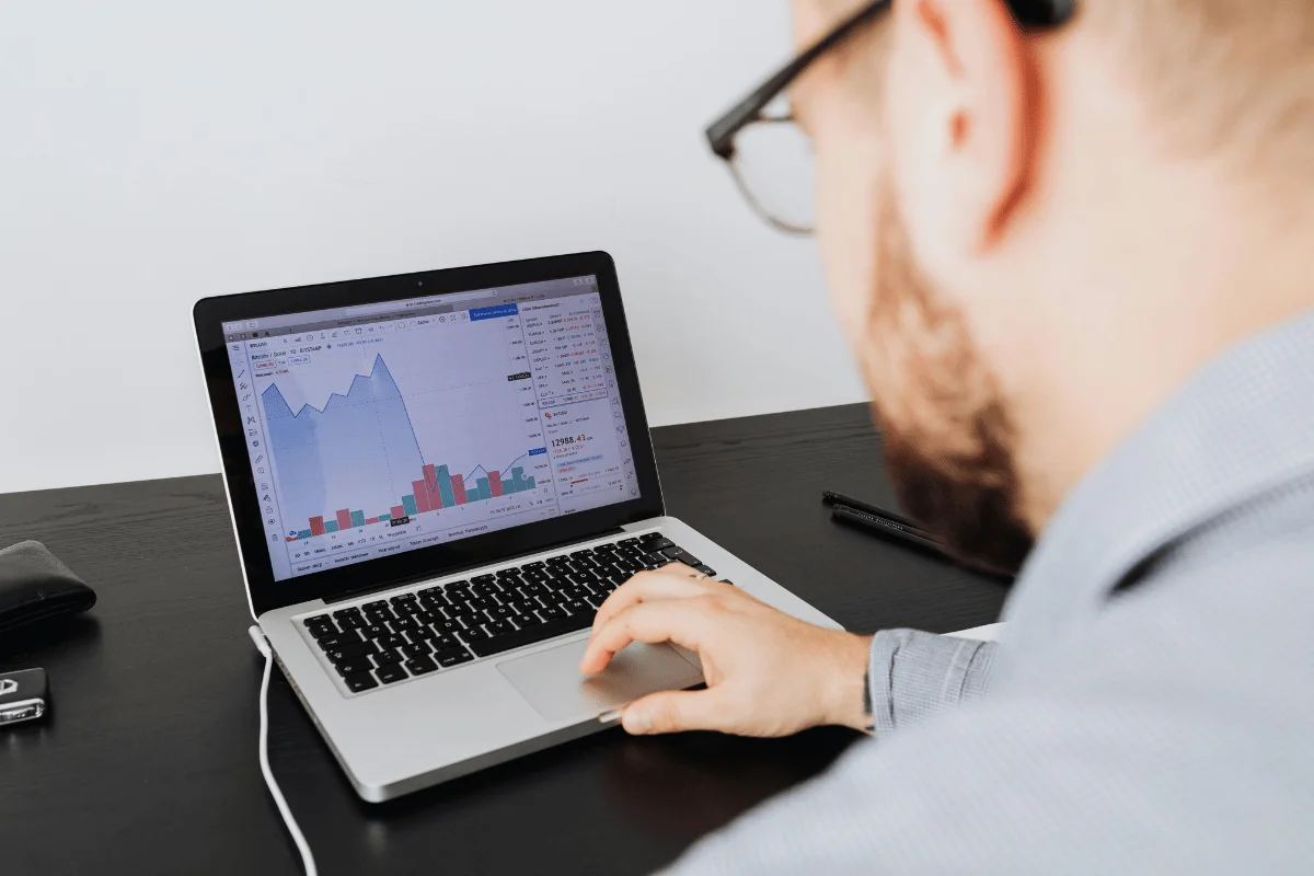 Man analyzing stock market trends on a laptop screen.