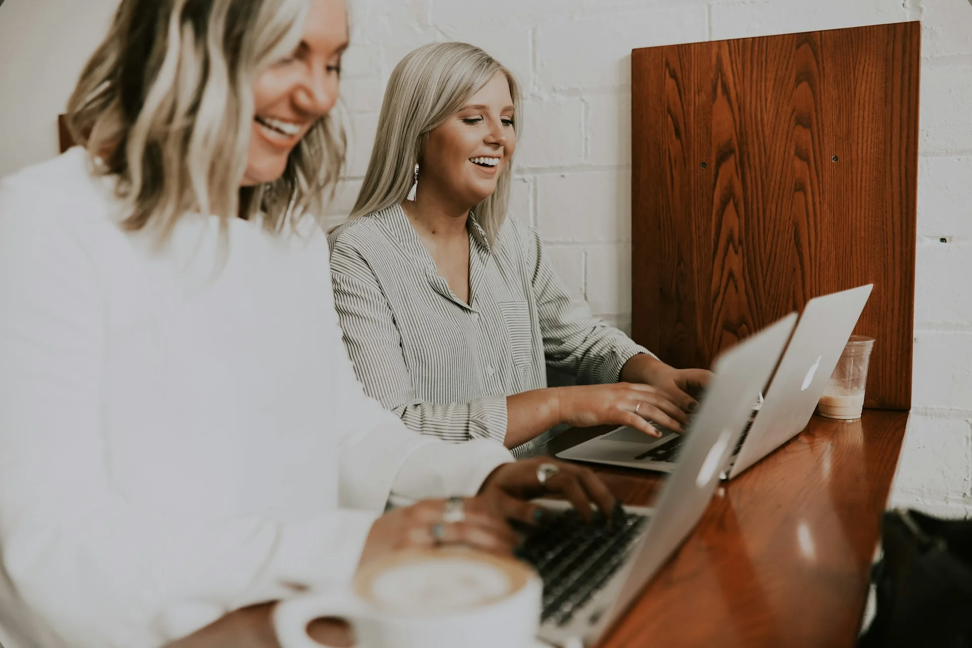 Two smiling women working on laptops.