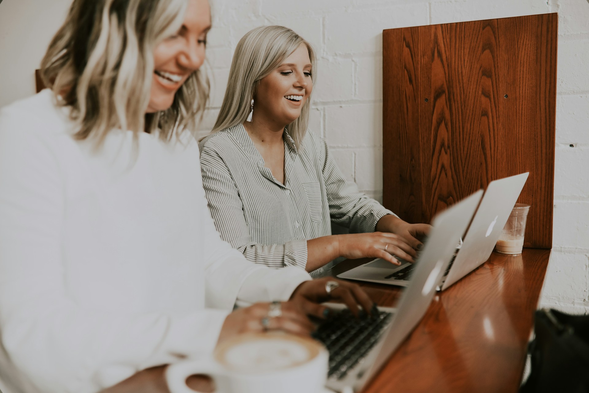 Two smiling women working on laptops.