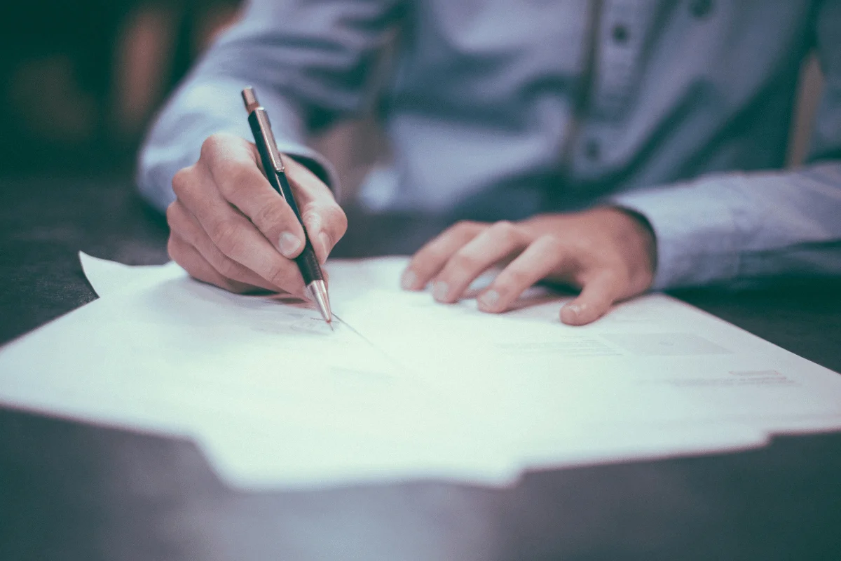 Individual using a pen to sign a document.