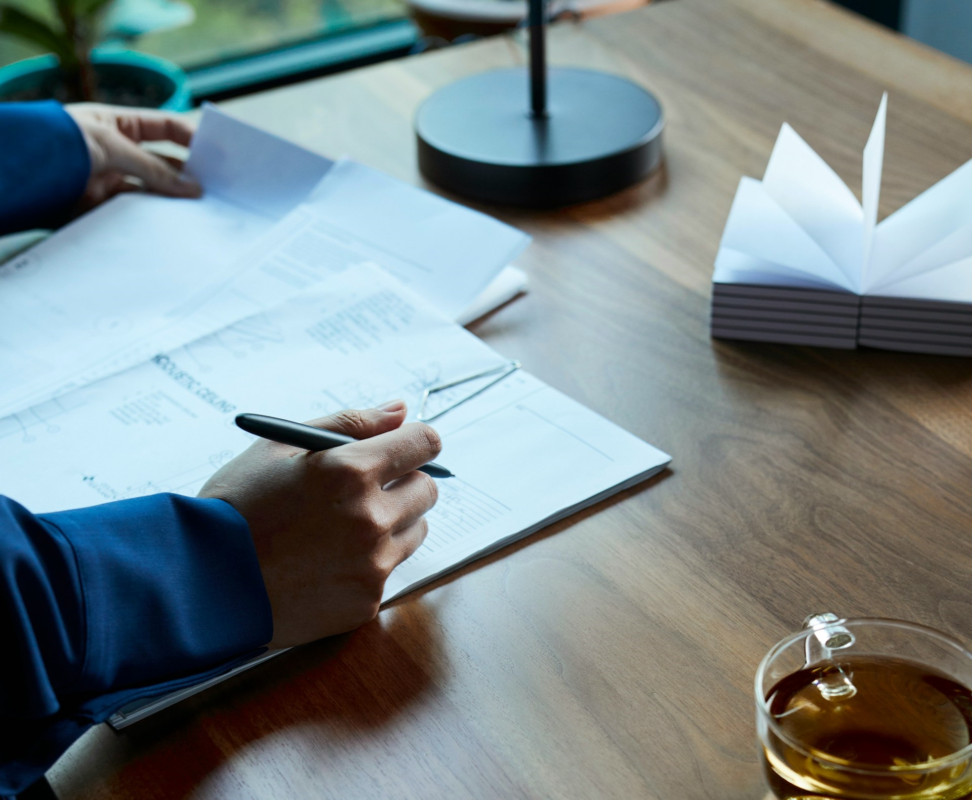 A man with a pen at his desk recording bookkeeping transaction on paper.