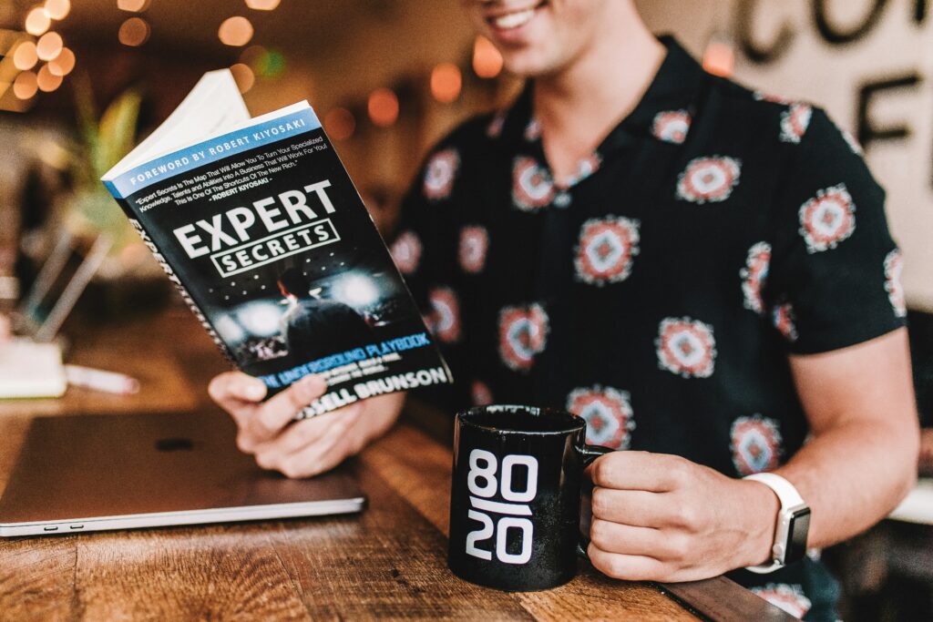A man reading a book that says "Expert Secrets"