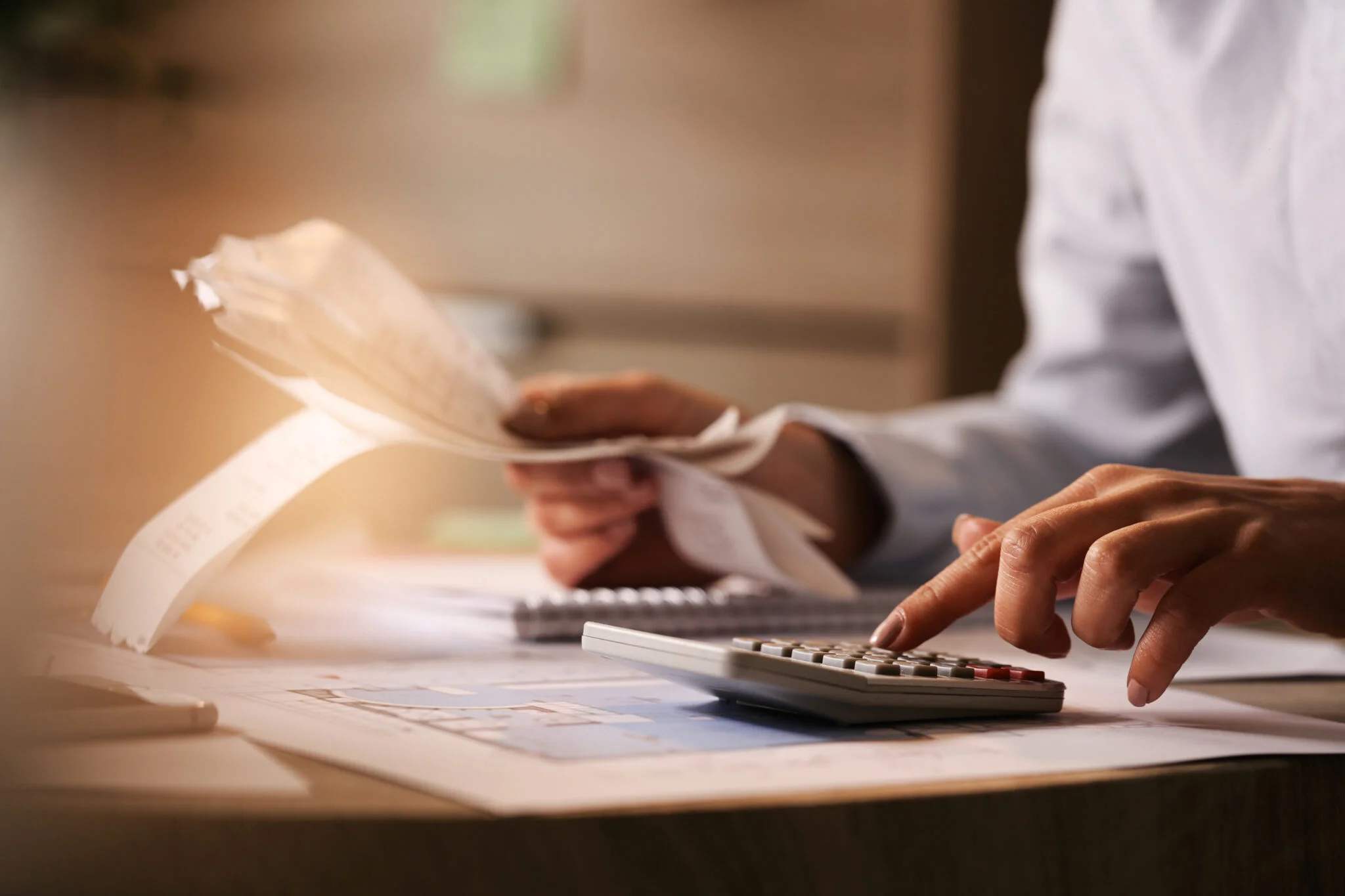 Person using a calculator while reviewing receipts and financial documents.