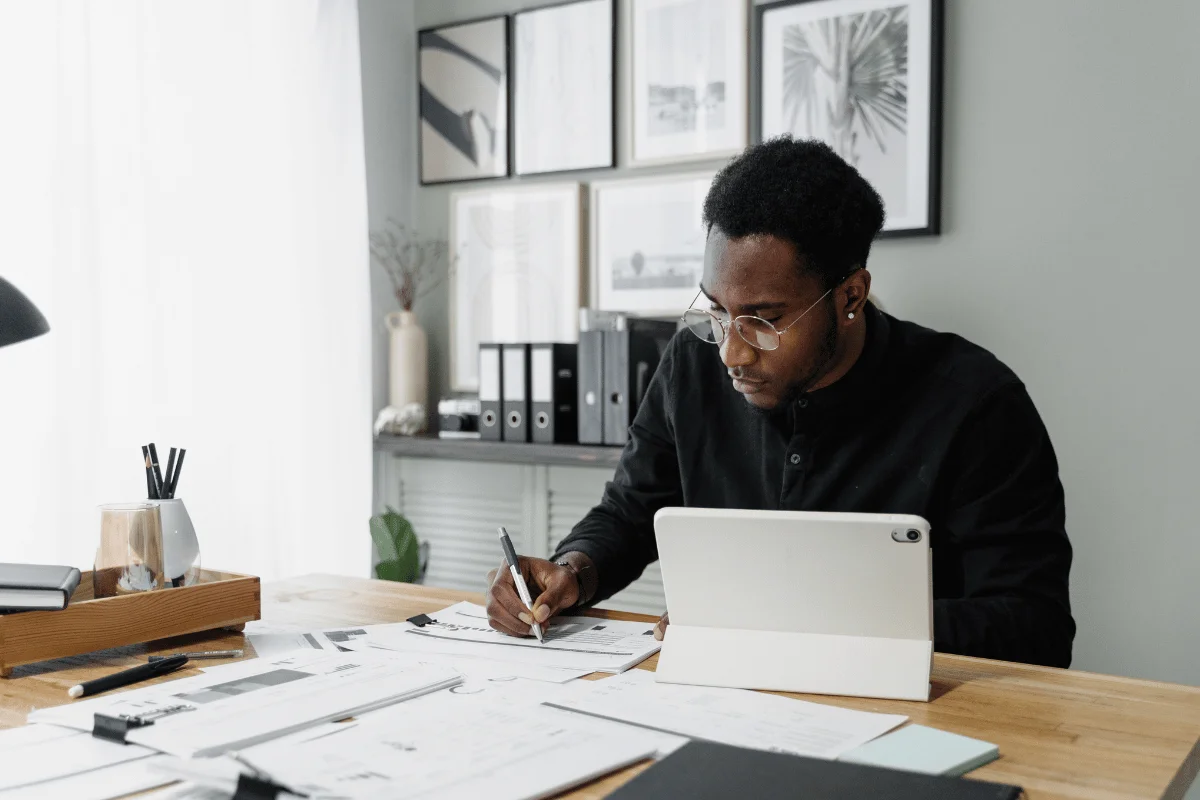Focused businessman analyzing financial data on paper and a tablet.