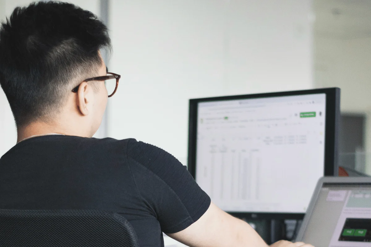 Person working on financial data displayed on a computer screen.