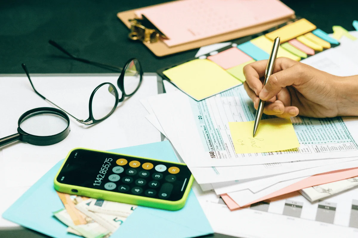 Tax preparation with a smartphone calculator, sticky notes, and financial documents.