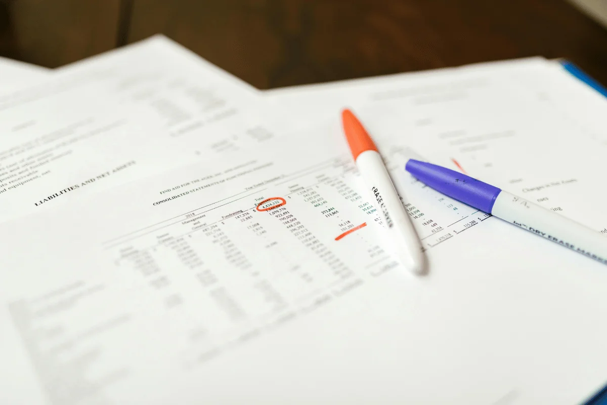 Highlighted financial figures on printed reports with colorful pens.