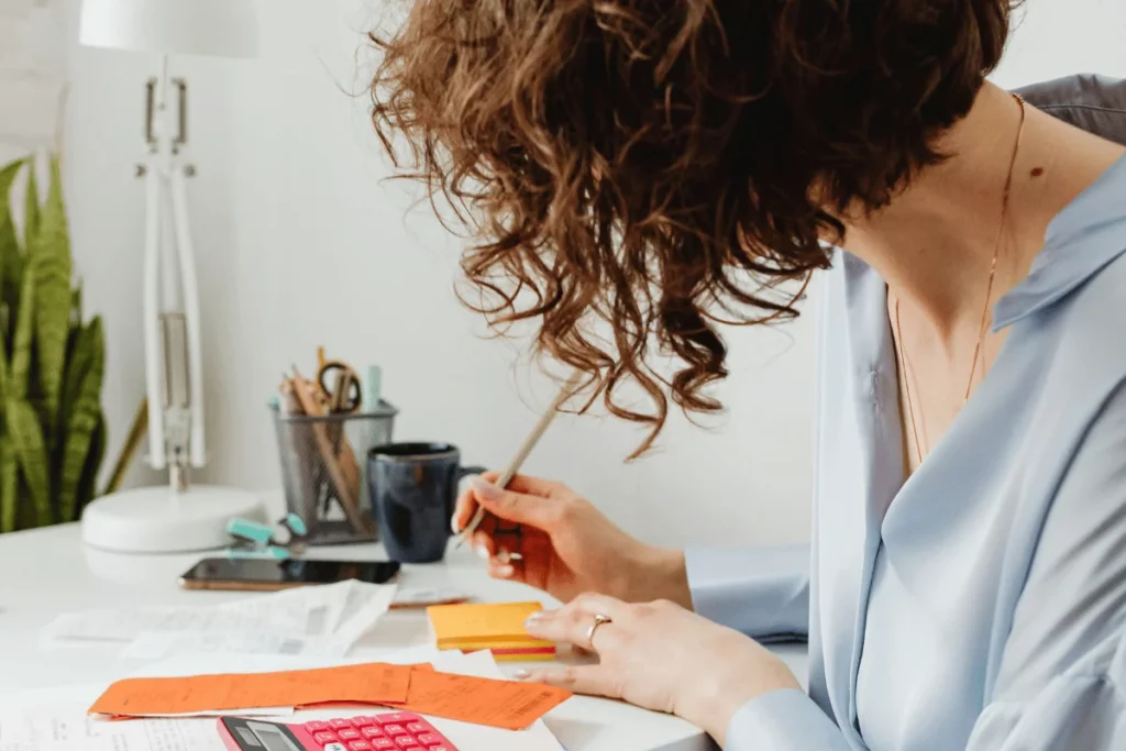 Professional woman writing on sticky notes while working.