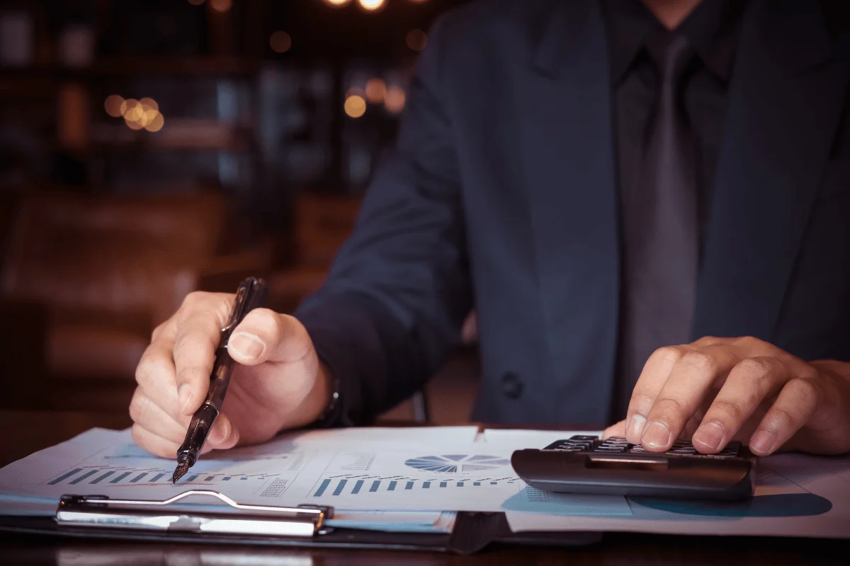 Business professional analyzing financial data with a pen and calculator.