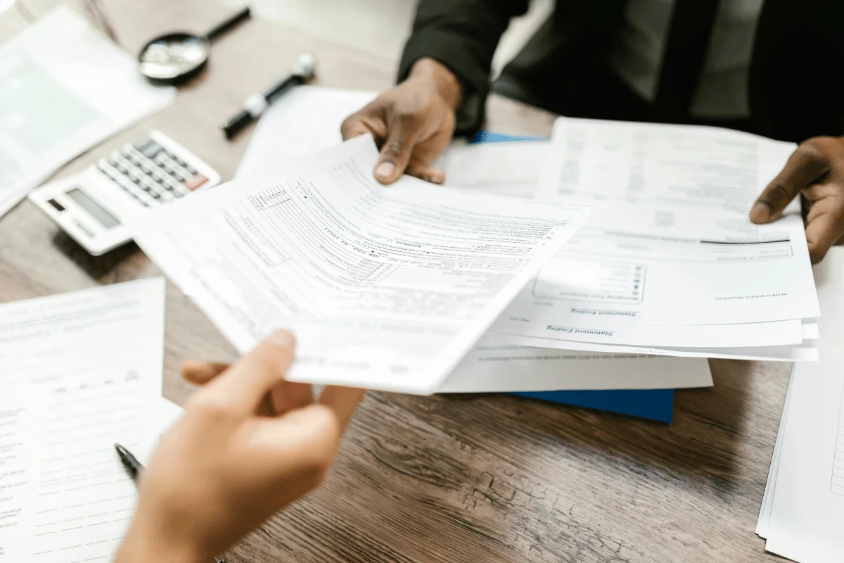 Two professionals reviewing financial documents and tax forms at a desk.