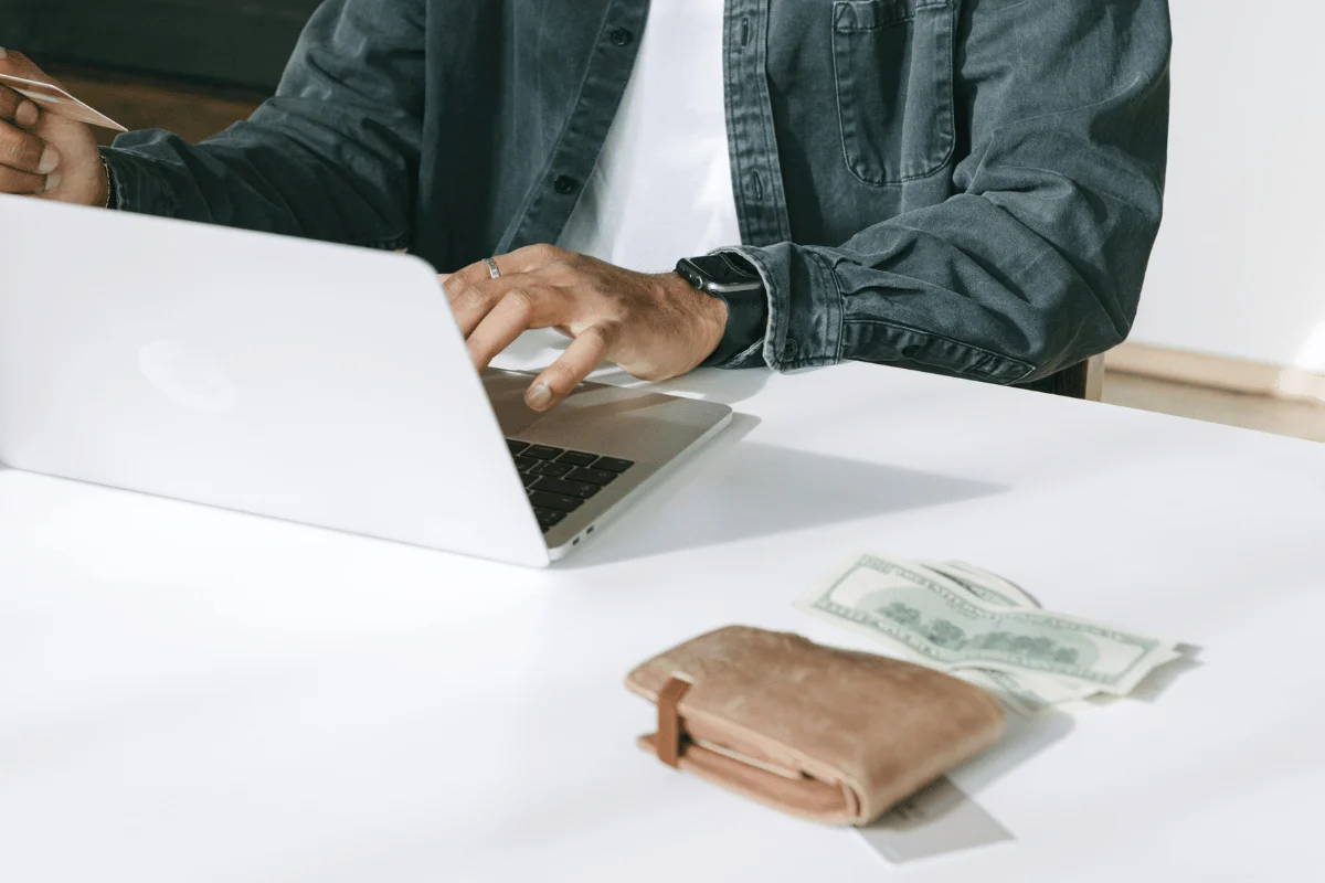 Close-up of a professional using a laptop at a white desk.