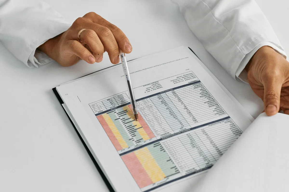 A hand holding a pencil while reviewing receipts and writing in a notebook with a calculator nearby.
