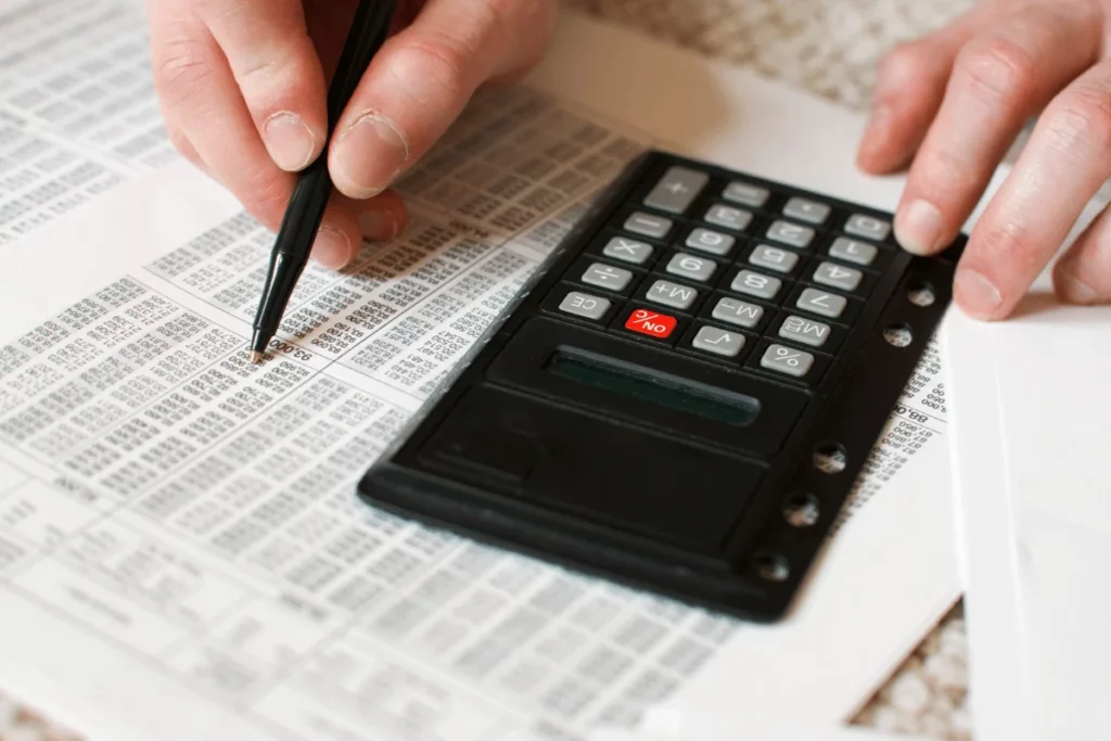Person using calculator and pen to check financial data.
