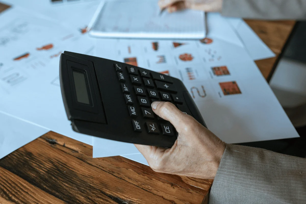 Business professional using calculator on financial charts.