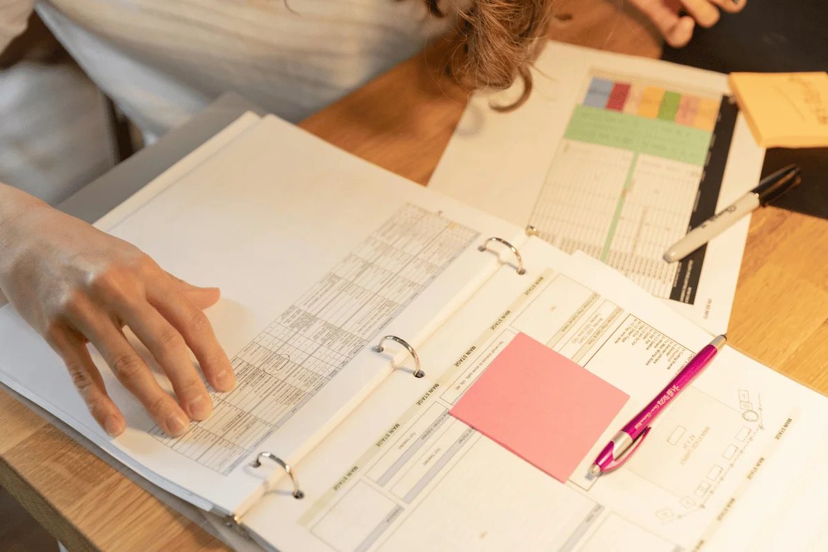 Hand flipping through financial documents in office binder.