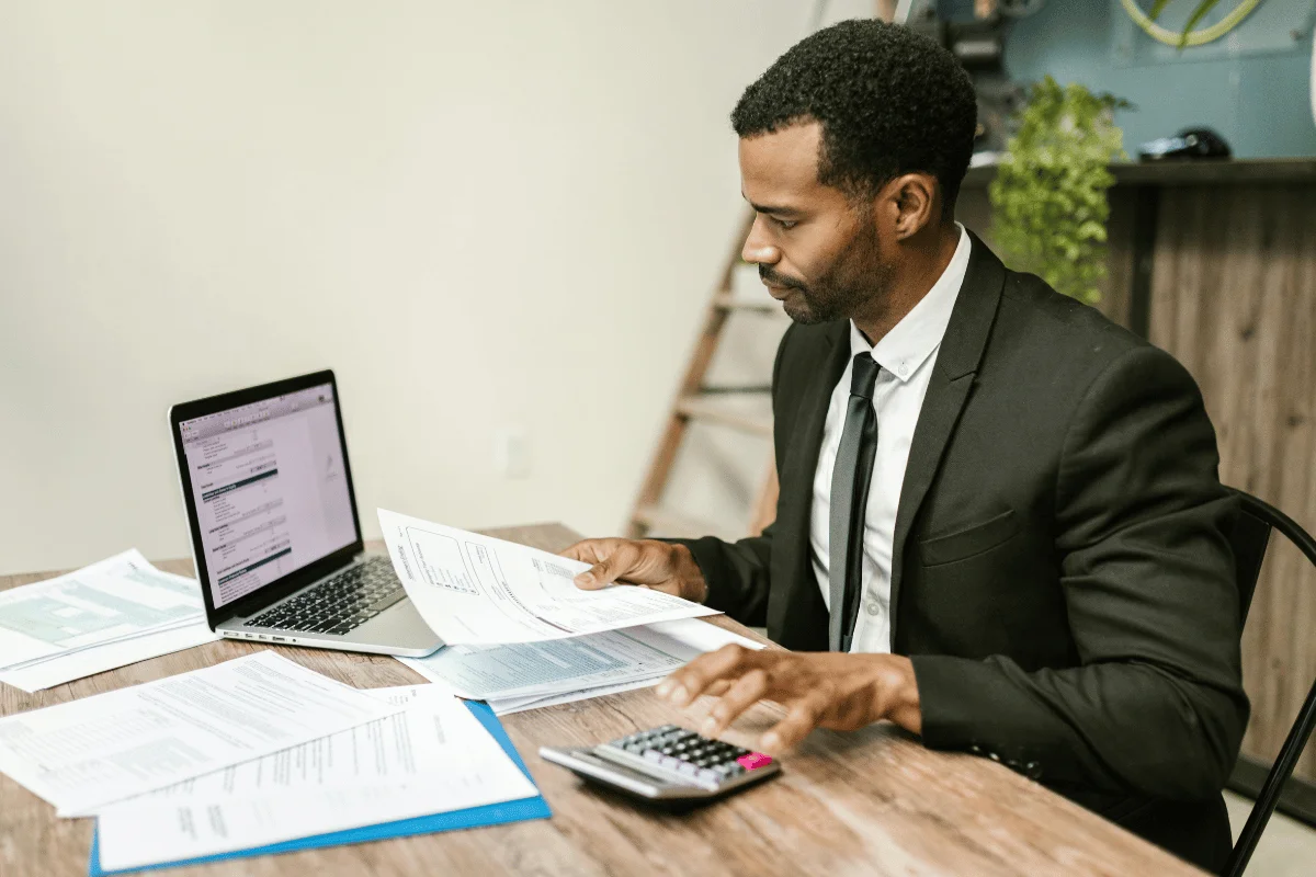 Financial professional analyzing documents and calculating figures for bookkeeping and reconciliation.