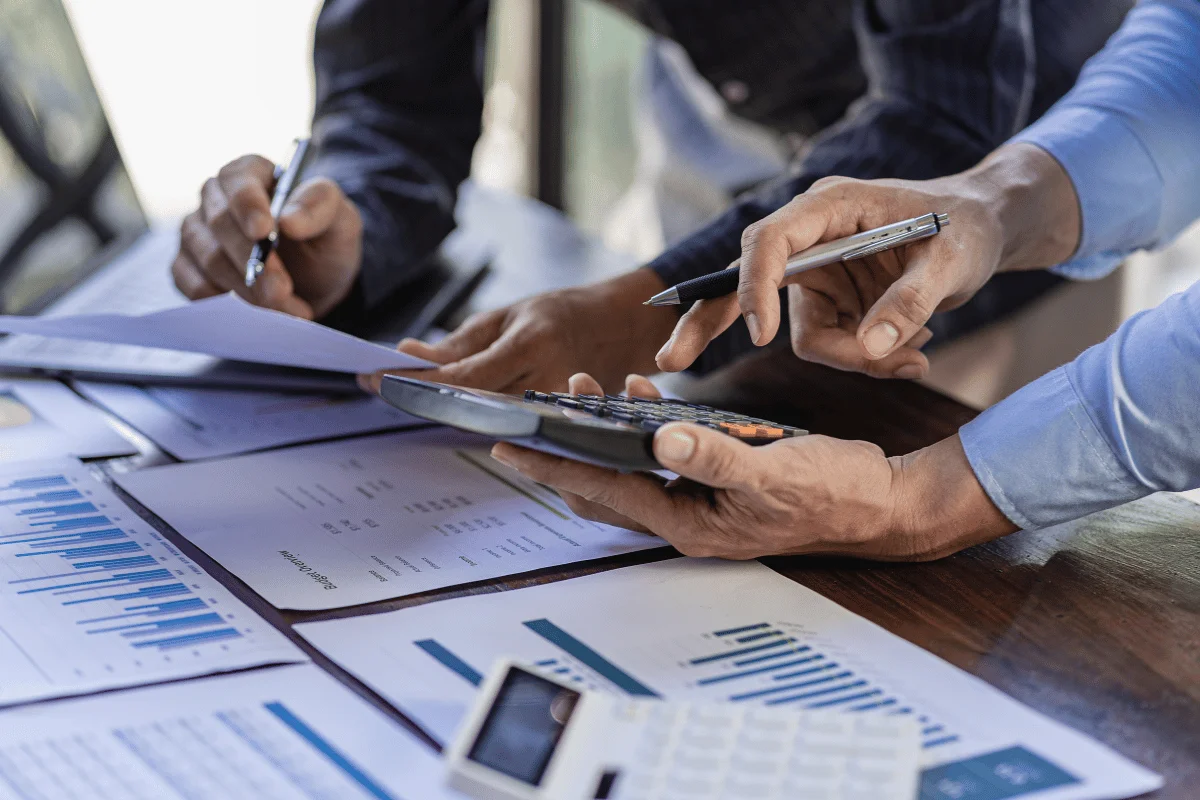 A group of professionals collaborating on financial data using a calculator and charts.