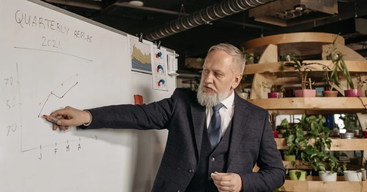 Businessman presenting quarterly tax planning service business strategy on whiteboard in modern office.