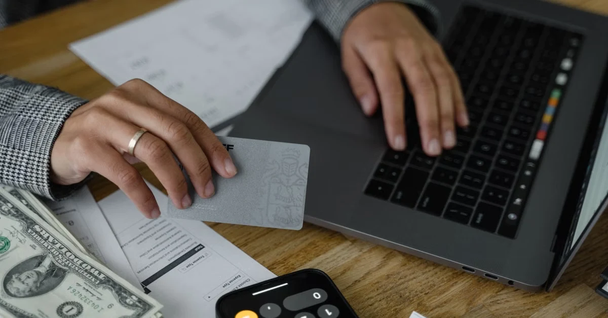Hands using laptop and calculator with dollar bills and documents for year end tax planning review.
