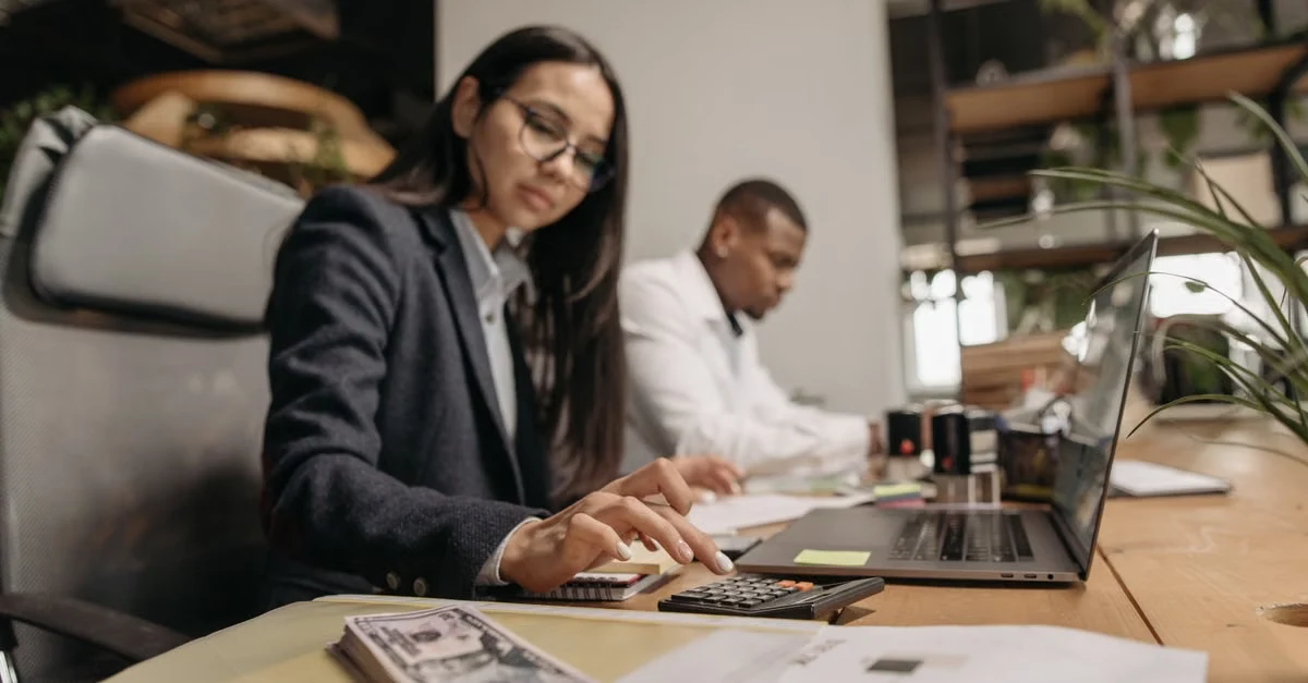 Business owners working on tax planning strategy at desk with laptop and financial documents.